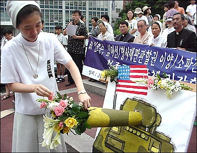 29일 명동성당 들머리에서 한 수녀가 평화를 염원하는 의미에서 손에 들고 있던 꽃을 모형 장갑차 포문에 꽂아넣고 있다. 